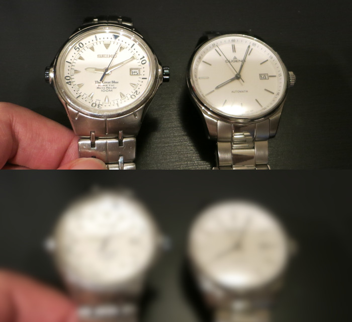 Zwei Uhren mit weißem Zifferblatt, eine mit silbrig glänzenden, die andere mit schwarzen Zeigern. Darunter noch einmal das gleiche Bild in verschwommener Form.