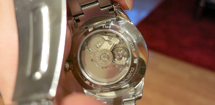 Gläserne Rückseite einer Armbanduhr, durch die man die Mechanik im Inneren sieht.