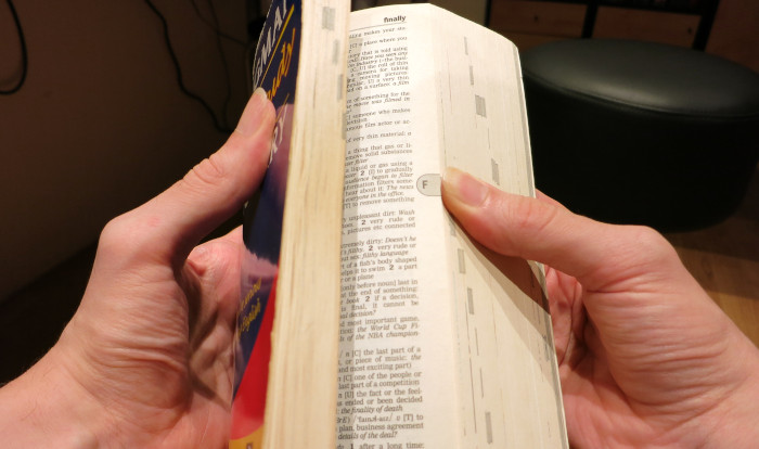 Wörterbuch beim Durchblättern mit der rechten Hand, sodass man nur wenige Zentimeter der rechten Seiten sieht.