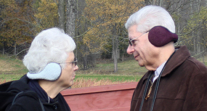 Zwei ältere Personen mit Ohrenschützern, die im Nacken zusammengehalten werden.