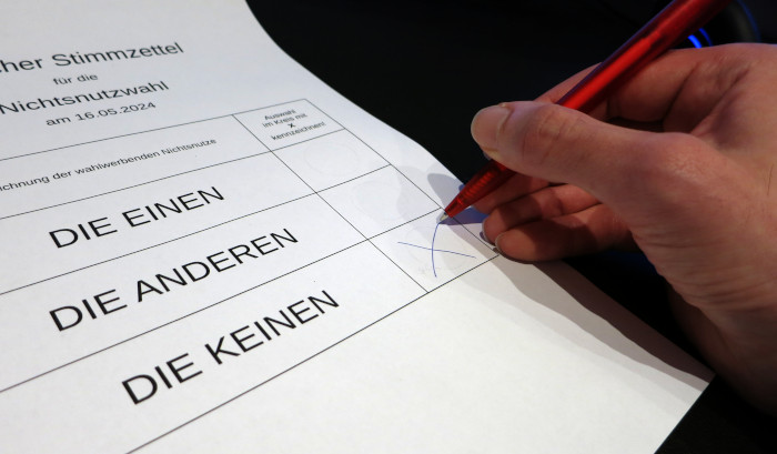 Foto von einem »Stimmzettel für die Nichtsnutzwahl« mit den Auswahlmöglichkeiten »Die Einen«, »Die Anderen« und »Die Keinen«. Eine Hand mit Kugelschreiber kreuzt die letzte Option an.
