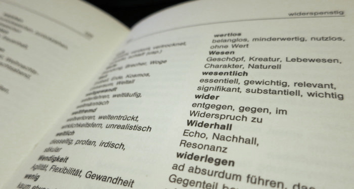 Aufgeschlagenes Wörterbuch, in dem statt Erklärungen ähnliche Begriffe stehen. Im Fokus steht zum Beispiel das Wort »wider« mit den Synonymen »entgegen«, »gegen« und »im Widerspruch zu«.