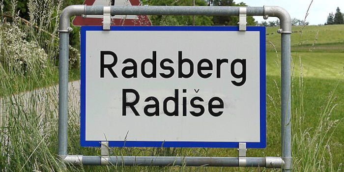 Ortstafel mit den beiden Beschriftungen »Radsberg« und »Radiše«.
