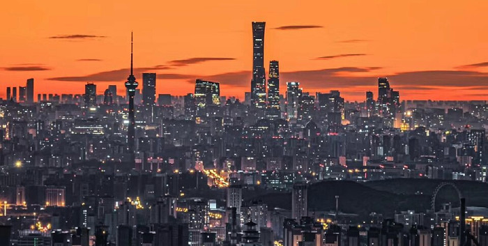 Skyline einer Stadt mit Wolkenkratzern vor einem orangen Himmel.