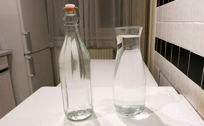 Glasflasche und Glaskaraffe nebeneinander.
