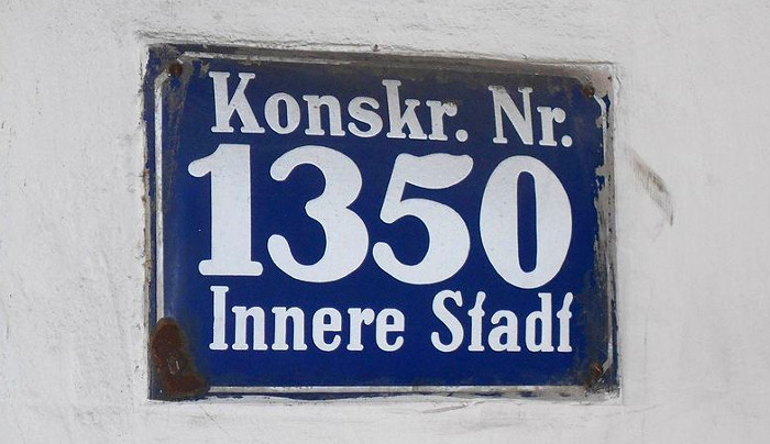 Schild mit Beschriftung »Konskr. Nr. 1350 Innere Stadt«.